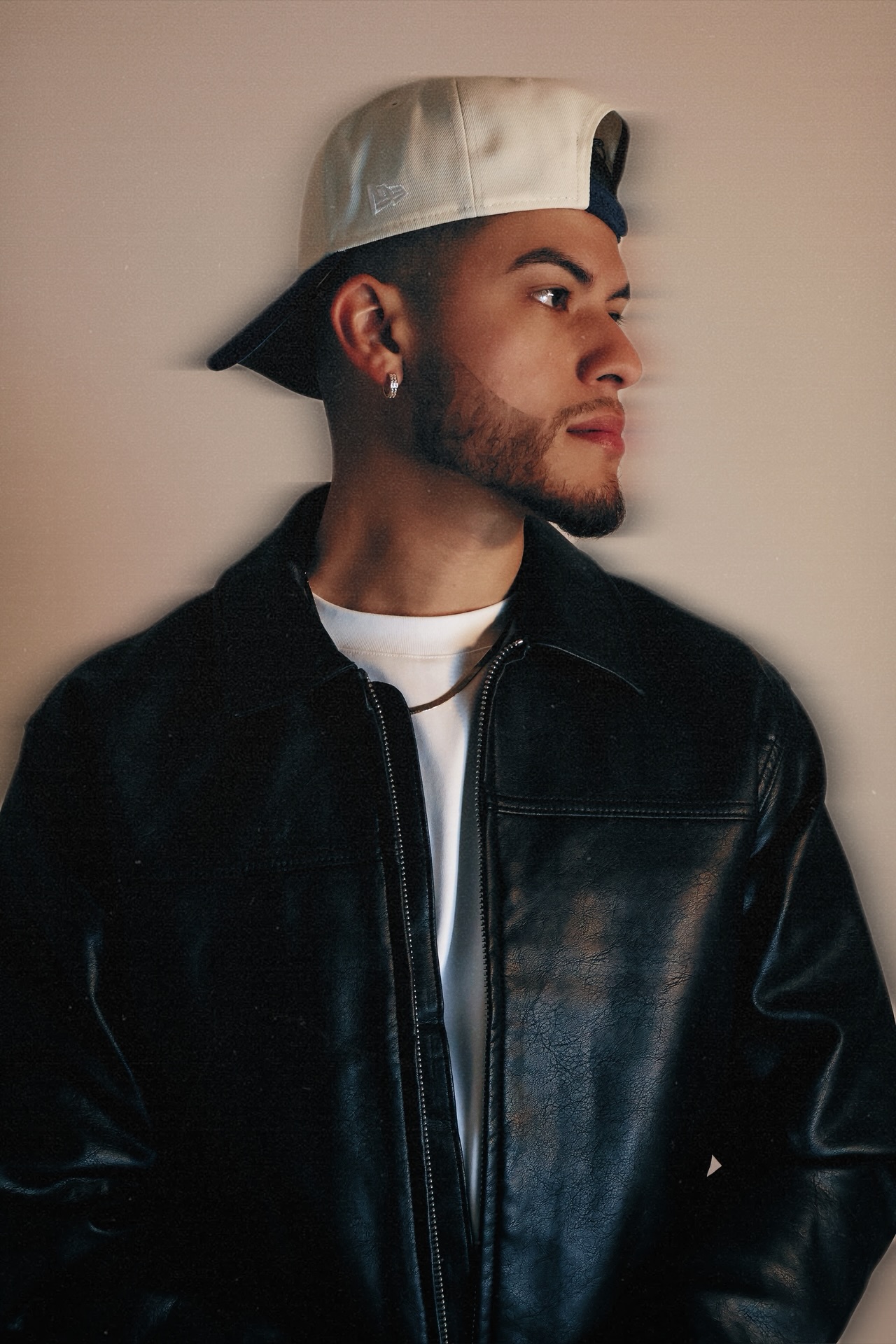 J SUPA wearing a black leather jacket and backwards cap